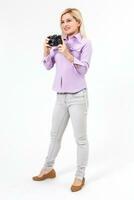 Young beautiful smiling blond woman holding a micro four thirds photo camera. Isolated over white background.