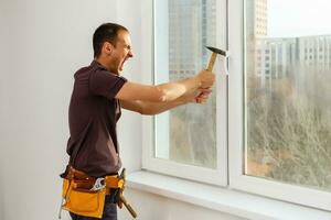 worker repairs windows with a hammer photo