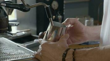 el café máquina es espumando leche. de barista manos sostener un jarra de leche. video