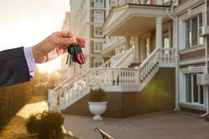 Holding house keys on house shaped keychain in front of a new home photo