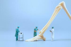 Miniature people , Anatomy model of the human ankle joint with a doctor on a blue backdrop photo