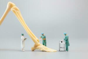 Miniature people , Anatomy model of the human ankle joint with a doctor on a grey backdrop photo