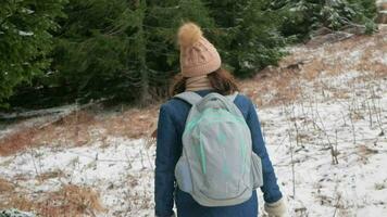 mulher sobe morro acima, neve e inverno. viajante com mochila anda em. video