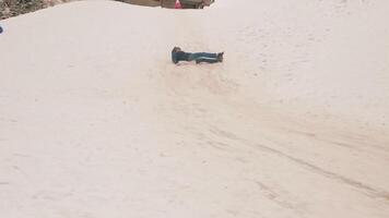 man rides down slide, winter, mountains, return to childhood, happiness and a smile. video