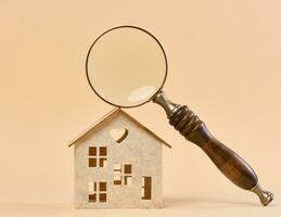 Wooden house and a magnifying glass, representing the concept of real estate purchase, rental growth photo