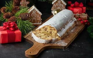 Christmas pastries stollen sprinkled with powdered sugar on the table, festive dessert photo