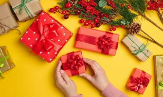 Woman is packing gifts, the pre-holiday bustle and preparations for Christmas. Gifts wrapped in red paper photo