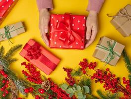 Woman is packing gifts, the pre-holiday bustle and preparations for Christmas. Gifts wrapped in red paper and tied with ribbon photo