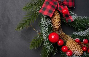 A circular Christmas wreath made of fir branches and other decorations on a black chalkboard photo