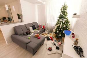 Messy living room interior with Christmas tree. Chaos after party photo