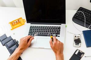 Man repairing broken laptop in workshop photo