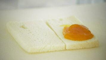 Chef anointing marmalade peach on a slice of bread with a spoon video