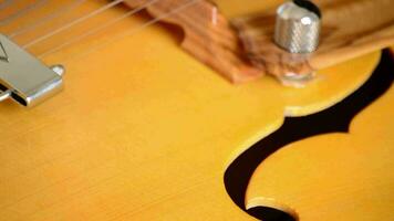 Detail of bridge, strings and efes of a jazz electric guitar rotating video