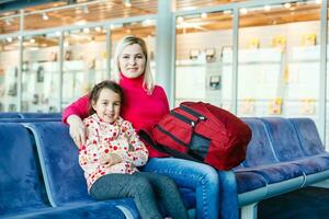 happy young mother with daughter at airport while waiting for their flight photo