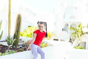 beautiful little girl stands among a small green leaf beautiful plants in spring and summer on a sunny day. photo