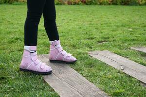 Child cerebral palsy disability with legs orthosis walking on a park photo