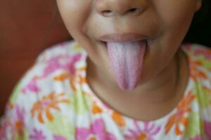 child shows his tongue closeup photo