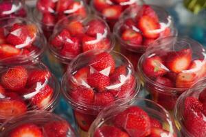 maduro rojo fresas en. el plastico envase de venta a tienda foto