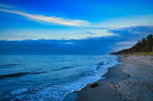 Sunset on the west beach on the Baltic Sea. Waves, beach, cloudy sky and sunshine photo