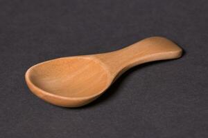 Macro photography of bamboo wooden spoon isolated on black paper background photo