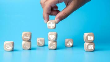 Concept of health insurance and medical. Human hold wooden block with icons about health insurance and access to health care, health care planning on a blue background. photo