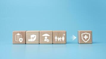 Concept of health insurance and medical. Wooden block with icons about health insurance and access to health care, health care planning on a blue background. photo