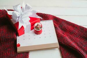 Gift boxes on knitted scarf a red scarf on white wooden table top view. Warm new year. Flat lay, top view. photo