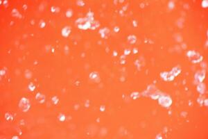 Orange water with ripples on the surface. Defocus blurred transparent white-black colored clear calm water surface texture with splash and bubbles. Water waves with shining pattern texture background. photo