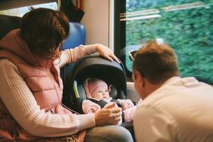 Young happy parents traveling with little baby by train photo