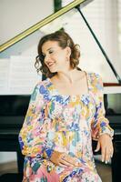 Portrait of beautiful young woman sitting next to piano, wearing colorful dress photo