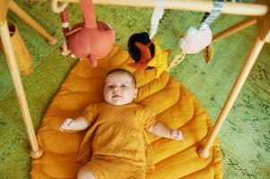 Adorable little baby playing with wooden baby gym photo