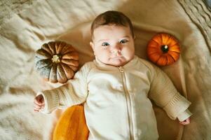 Adorable baby lying on blanket, playing with mini pumpkin photo