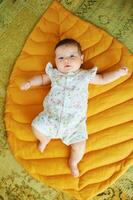 Portrait of adorable 6 months old baby lying on yellow play blanket photo