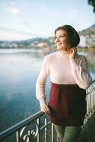 Outdoor portrait of beautiful young woman relaxing by mountain lake, cold weather photo