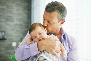 Middle age father holding adorable  sleeping baby photo