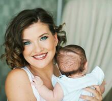 Close up portrait of beautiful young mother holding little baby photo