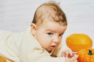 Autumn portrait of adorable baby playing with mini pumpkin photo