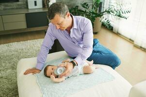 Father bottle feeding little baby after work, parenthood concept photo