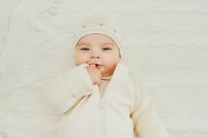 Portrait of adorable baby lying on white blanket, wearing hat photo