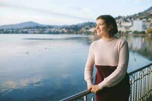 Outdoor portrait of beautiful young woman relaxing by mountain lake, cold weather photo