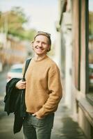 Outdoor portrait of handsome young man wearing beige fuzzy fleece sweater, posing on city street background photo