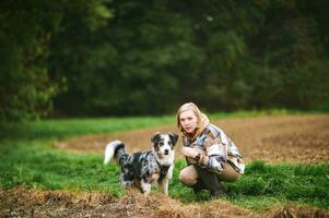 Outdoor portrait of beautiful young woman playing with australian shepherd dog photo