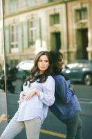 Outdoor portrait of young asian woman leaning on mirror wall, street fashion photo