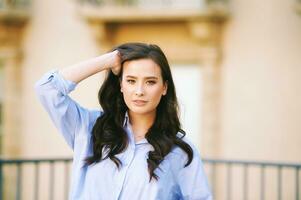 Fashion portrait of beautiful young woman, wearing blue shirt, posing outdoors photo