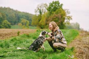 Outdoor portrait of beautiful young woman playing with australian shepherd dog photo