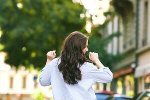 Fashion portrait of beautiful young woman, wearing blue shirt, posing outdoors photo