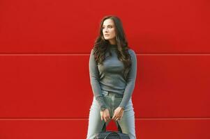 al aire libre retrato de joven bonito mujer posando en rojo fondo, vistiendo caqui capucha foto