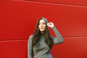 Outdoor portrait of young pretty woman posing on red background, wearing khaki hoodie photo