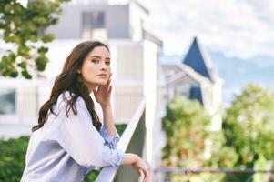 Fashion portrait of beautiful young woman, wearing blue shirt, posing outdoors photo