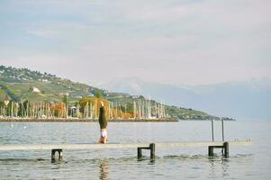 Outdoor portrait of young beautiful woman practicing yoga by the lake photo